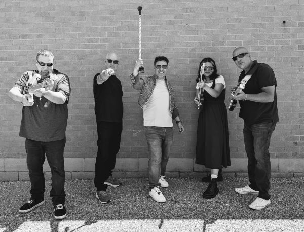 Group of five posing with toy guns in front of a brick wall.