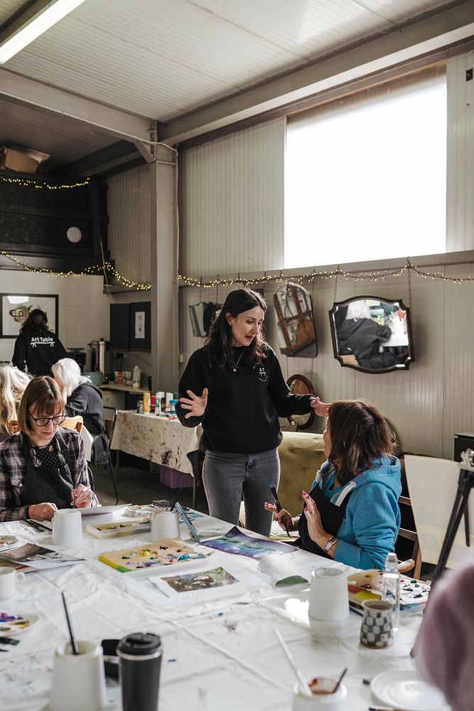 Art teacher instructs student in art class. People working on paintings
