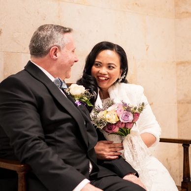 Wedding Photography, Bride and Groom sitting on a wooden bench looking at each other