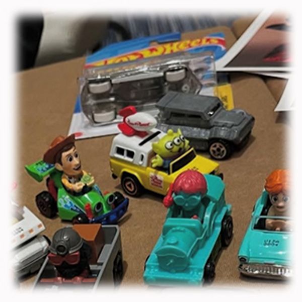 Collection of colorful toy cars and character figures on a table.
