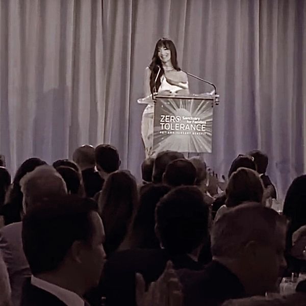 A woman speaks at a Zero Tolerance Sanctuary event with a large audience.
