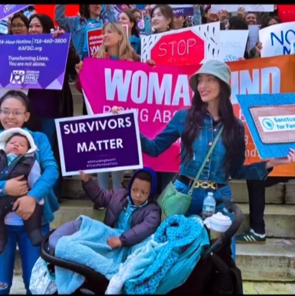 A group holds signs advocating for survivors and women's rights at a rally.