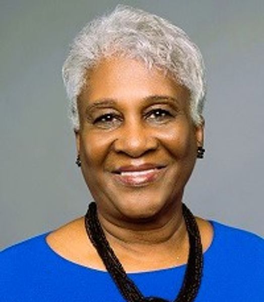 Smiling elderly woman with white hair in a blue top.