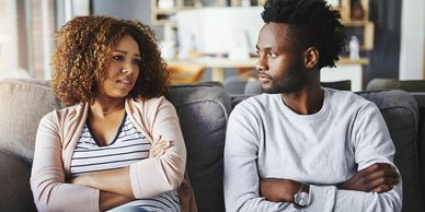 Couple sitting on a couch, having a serious conversation.
