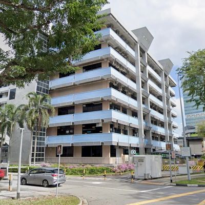 Multi-story parking garage with surrounding greenery and cars.
