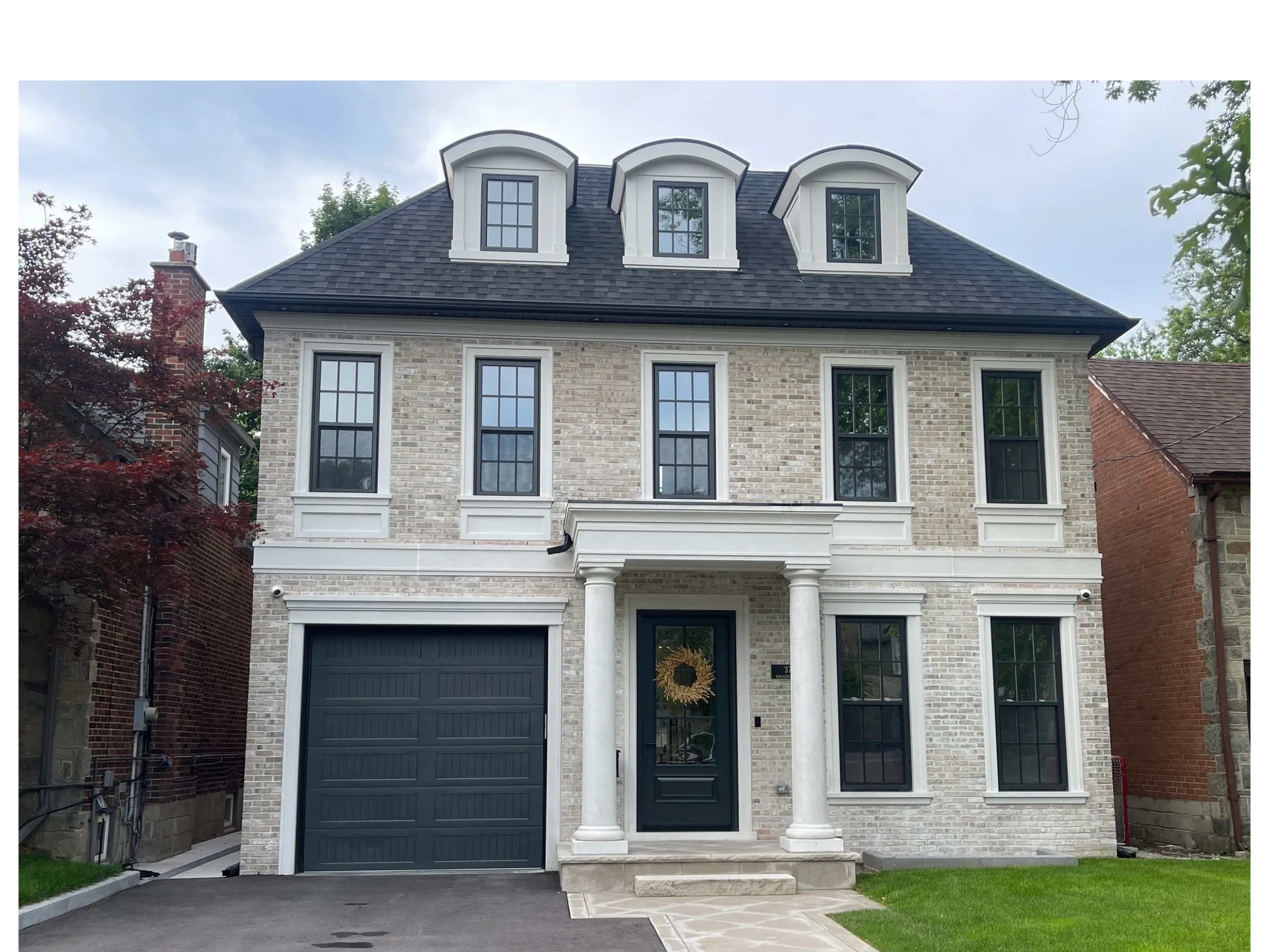 Elegant two-story brick house with dark windows and garage door.