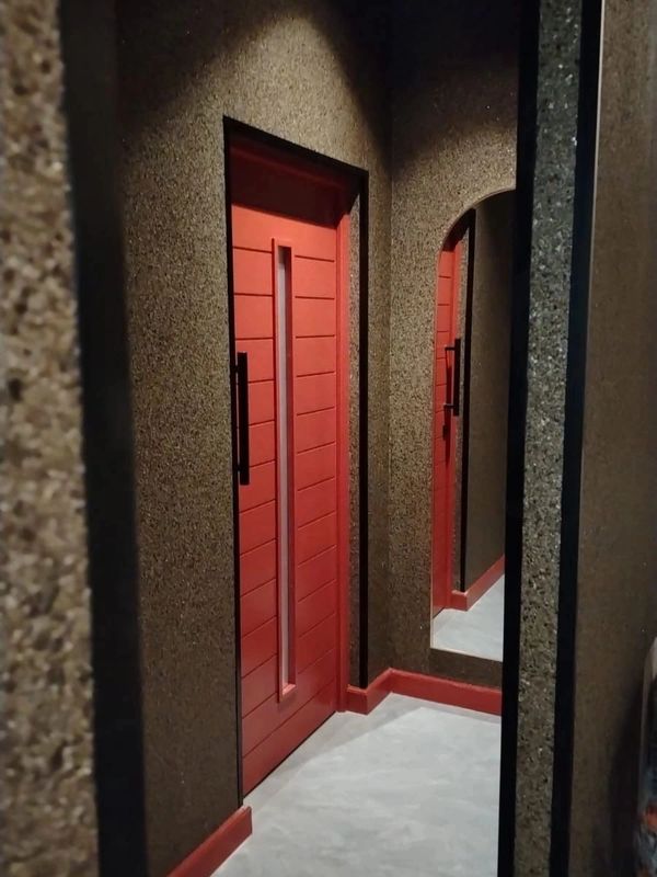 Modern red door in a textured hallway with a mirror reflecting it.