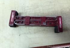 Red metal railway coupler on a concrete surface.