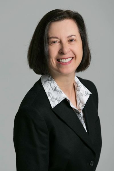 Professional woman in black blazer smiling at the camera.
