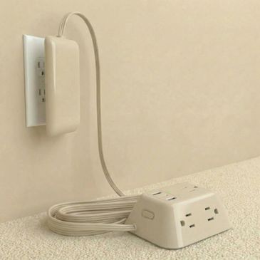 Compact wall-mounted power strip with coiled cable and multiple outlets.