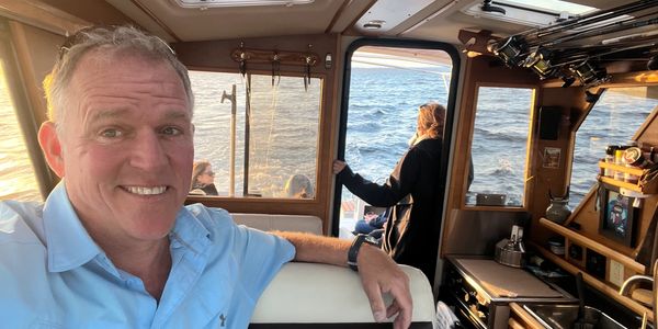 Man smiling on a boat during sunset.
