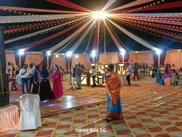 Brightly lit event tent with people socializing.