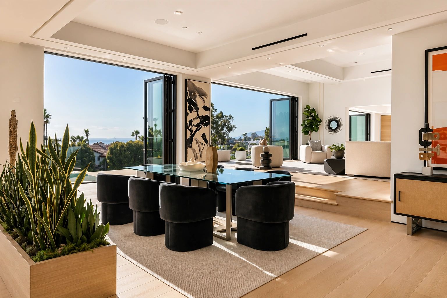 Modern dining area with black chairs and glass table overlooking a scenic view.