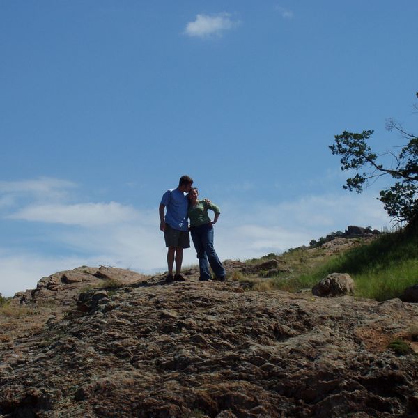 Photo of two people standing together on a hill.