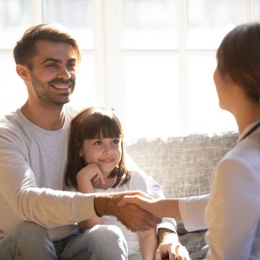 woman therapist shaking the hand of a father with a child in his lap