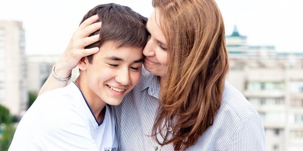 Mom with arm around her child's head smiling.