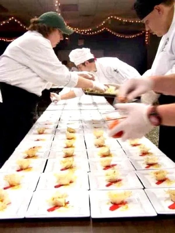 Chefs plating food in a kitchen.