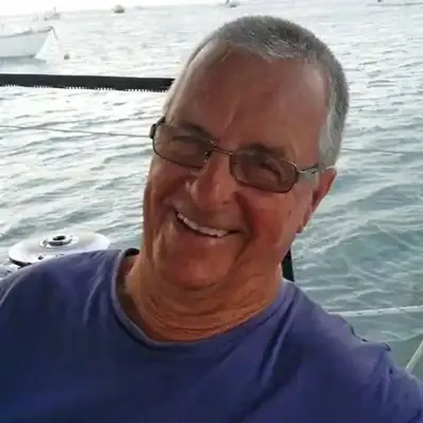 Smiling man wearing glasses on a boat near water.