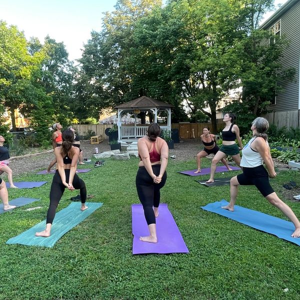 Group yoga session outdoors on mats in a lush backyard.