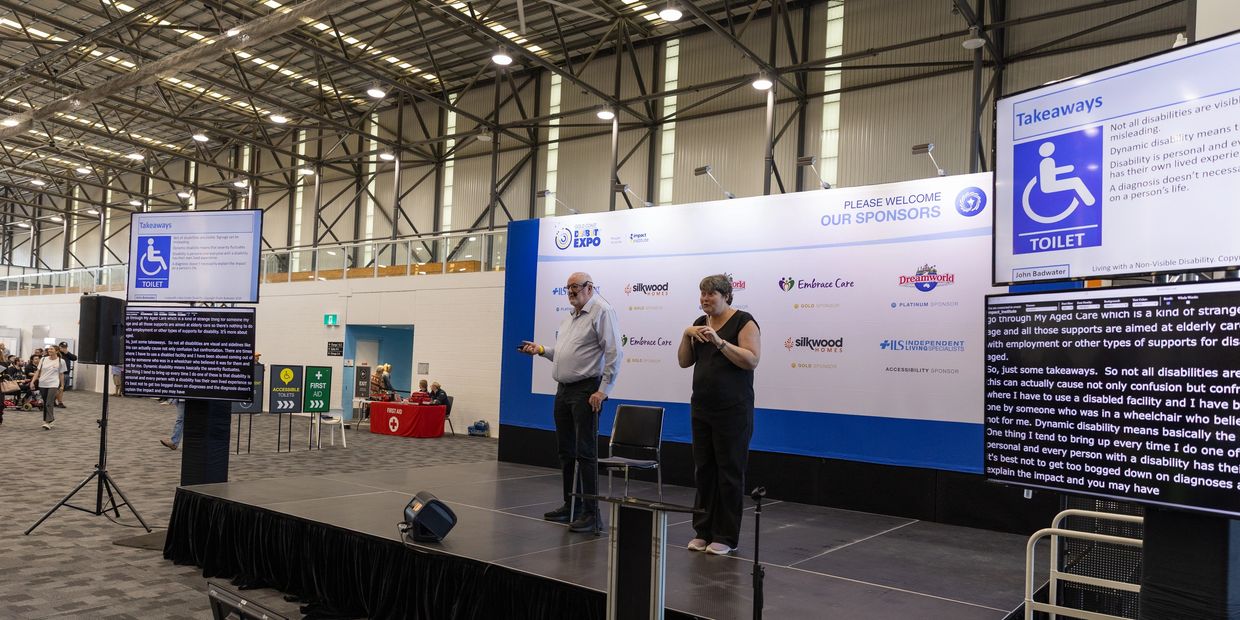 Presenter and signer on stage at a disability expo