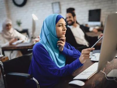 Focused woman in hijab working on a computer in a modern office.