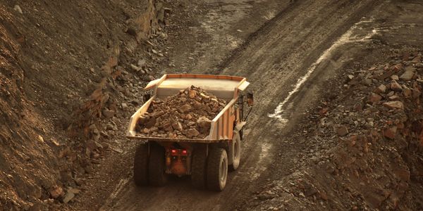 Dump truck carrying rocks on a dirt road.