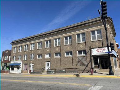 A three-story brick building with Leonard Realty sign on a street corner.