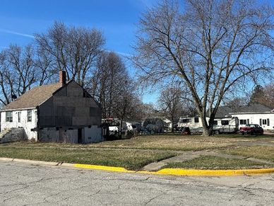 A residential area with houses, leafless trees, and a clear blue sky.