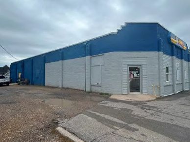 A blue and gray commercial building under a cloudy sky.
