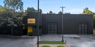 Modern black building with yellow entrance and outdoor seating area.