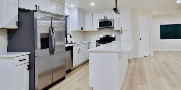 Modern kitchen with white cabinets and stainless steel appliances.