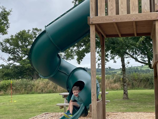 Young boy smiling as he comes out of the end of the enclosed slide. 