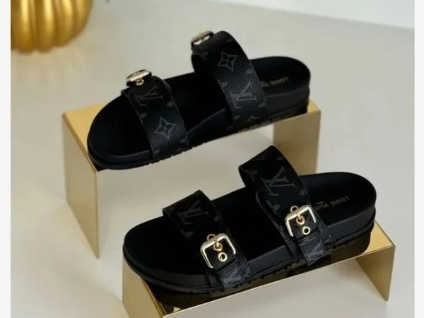 Black luxury designer sandals with gold buckles.