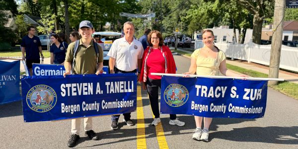 Four people holding Bergen County Commissioner banners at an outdoor event.