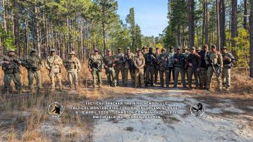 A group of tactical team members posing in a forested area.