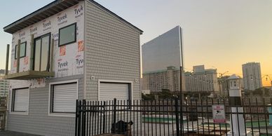Small building under construction with city skyline at sunset.