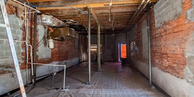 Empty room under renovation with exposed brick walls and ceiling beams.