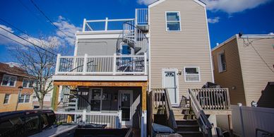 Two-story house with spiral staircase and wooden stairs under a blue sky.