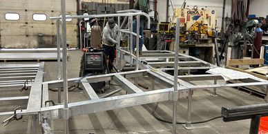 Two workers assembling a metal frame structure in a workshop.
