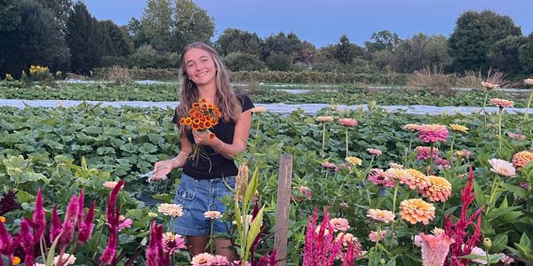 A young woman holding flowers in a colorful garden.