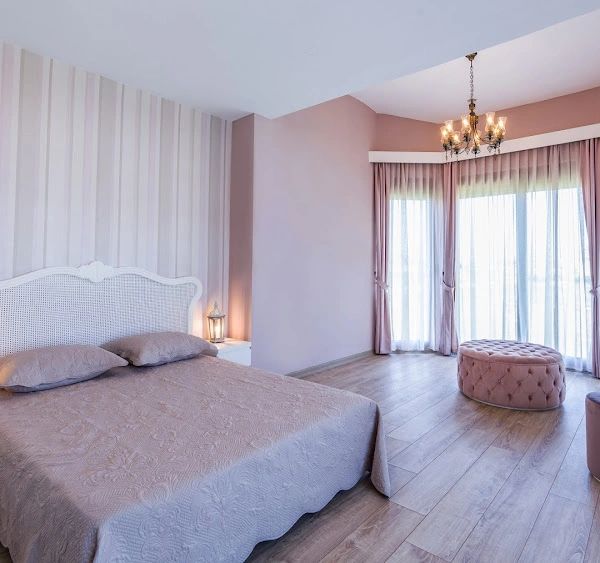 Elegant bedroom with soft pink tones and natural light.