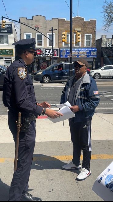 A police officer talks to a man on a city sidewalk.