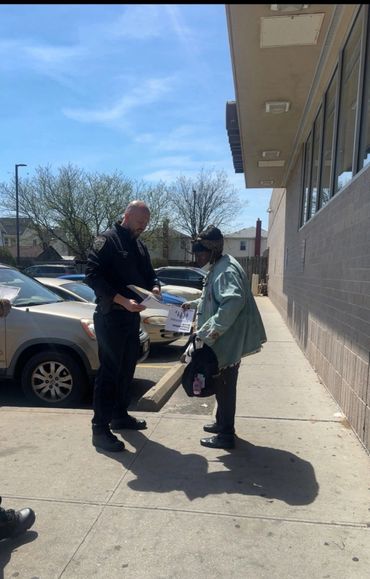 A man handing out papers to a woman outside on a sunny day.