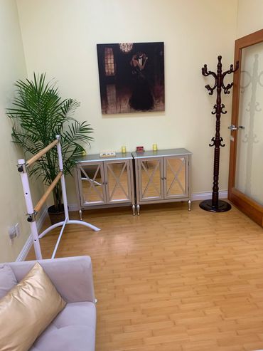 A cozy room with a sofa, ballet barre, mirrored cabinets, and a coat rack.