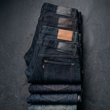 Stack of neatly folded blue jeans with varying shades and leather patches.