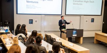 Speaker presenting on Canadian High-Tech Ventures in a classroom.