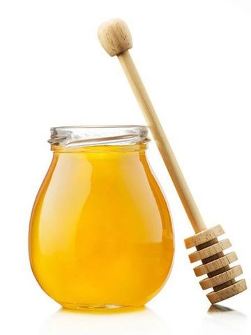 A jar of honey with a wooden honey dipper beside it.