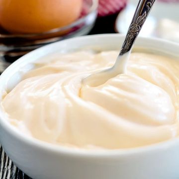 A bowl of creamy mayonnaise with a spoon.