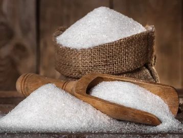 Granulated white sugar in a burlap sack and wooden scoop.