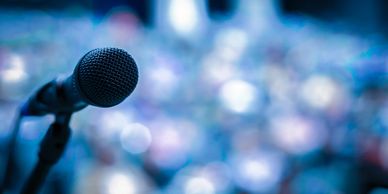 Close-up of a microphone with blurred audience lights in the background.